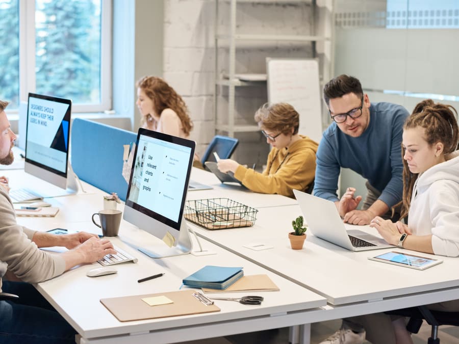 The Ledgerline team at their desks in a bright open office, two of them looking over a laptop together